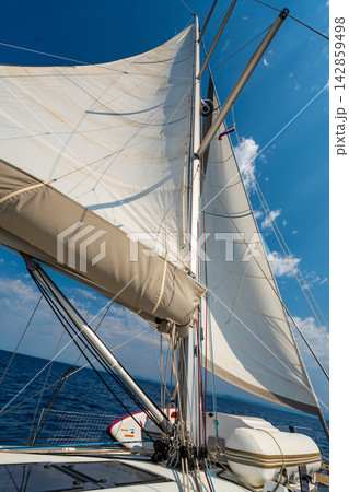 White sails filled with wind against a blue sky above a sailing yacht. Wind powered navigation and freedom at sea. 142859498