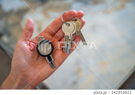 Hands holding traditional metal keys and an RFID key fob together. Concept of transition from mechanical locks to electronic access control and smart security technology 142859921