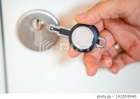 Close up view of hand using an RFID key fob to unlock an apartment door with electronic access system. Concept of keyless entry, smart security and modern access control. Close up view of hand using an RFID key fob to unlock an apartment door with electronic access system. Concept of keyless entry, smart security and modern access control. 142859940