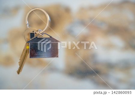 House keys with a house shaped keychain hanging on a wall hook. Concept of buying real estate, moving into a new home and property ownership. House keys with a house shaped keychain hanging on a wall hook. Concept of buying real estate, moving into a new home and property ownership. 142860093