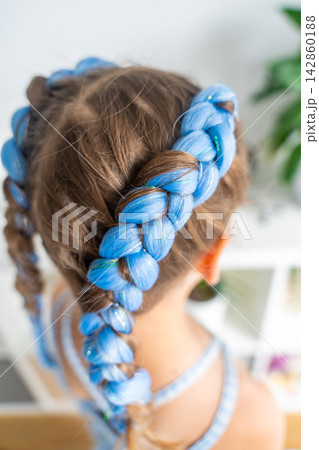 Colorful blue synthetic hair extensions braided into a young girl hairstyle. Trendy protective styling highlights creativity self expression and Generation Alpha fashion Colorful blue synthetic hair extensions braided into a young girl hairstyle. Trendy protective styling highlights creativity self expression and Generation Alpha fashion 142860188