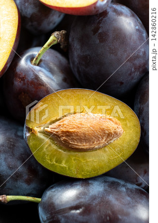 Fresh juicy plums whole and halved with seeds close up texture 142860216
