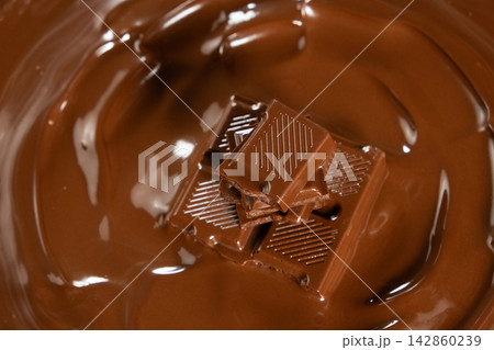 Macro view of chocolate bar pieces in melted chocolate pool Macro view of chocolate bar pieces in melted chocolate pool 142860239