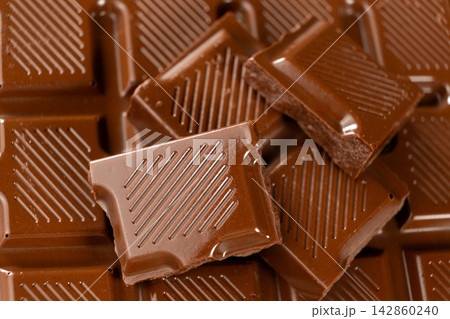 Broken milk chocolate bar pieces placed on chocolate block close up Broken milk chocolate bar pieces placed on chocolate block close up 142860240