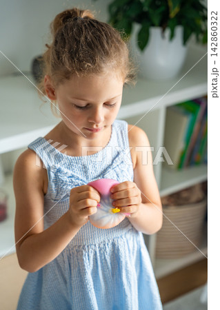 Child squeezes a soft squishy stress relief toy at home. Sensory play supports emotional regulation, relaxation and focus through tactile interaction. Child squeezes a soft squishy stress relief toy at home. Sensory play supports emotional regulation, relaxation and focus through tactile interaction. 142860322