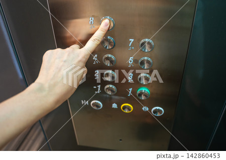 Person pressing the eighth floor button inside a modern elevator. Vertical transportation supports convenient access and efficient movement in residential buildings Person pressing the eighth floor button inside a modern elevator. Vertical transportation supports convenient access and efficient movement in residential buildings 142860453