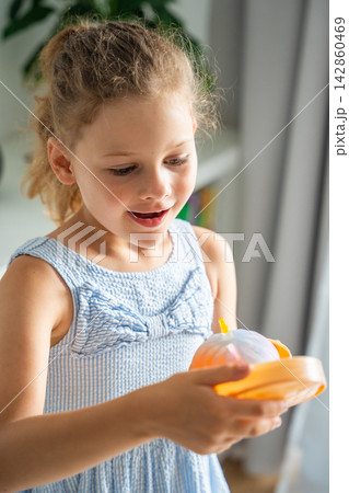 Child reacts with excitement after opening a surprise squishy toy at home. Joy and discovery capture the emotional reward of mystery unboxing. 142860469