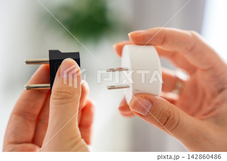 Electrical plug adapters with different socket standards in human hands. International power compatibility concept for travel, electronics and device charging. Electrical plug adapters with different socket standards in human hands. International power compatibility concept for travel, electronics and device charging. 142860486