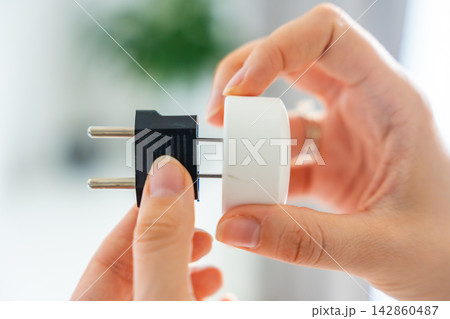 Electrical plug adapters with different socket standards in human hands. International power compatibility concept for travel, electronics and device charging. 142860487