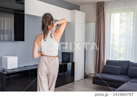 Young woman standing in modern apartment and holding house keys behind her back. Female home ownership and independent real estate achievement concept 142860787