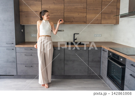 Young woman standing in modern apartment kitchen and holding house keys. Female home ownership and independent real estate investment concept 142861008