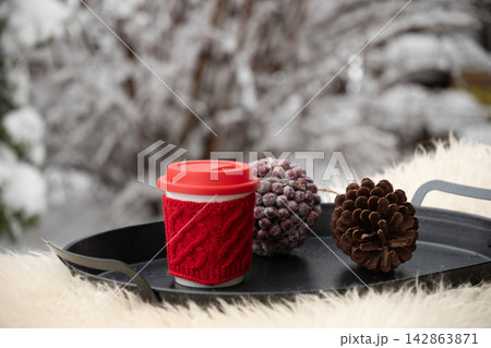 Red reusable coffee cup with winter decorations outdoors Red reusable coffee cup with winter decorations outdoors 142863871