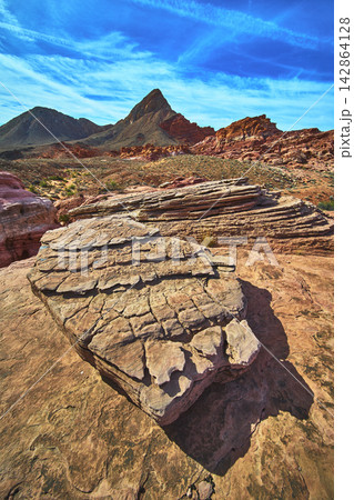 Layered Sandstone Formations Red Desert Landscape and Mountain Peaks Under Blue Sky Layered Sandstone Formations Red Desert Landscape and Mountain Peaks Under Blue Sky 142864128