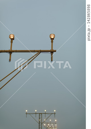 Airport runway approach lights against evening sky Airport runway approach lights against evening sky 142865898