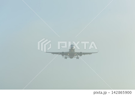 Airplane approaching in foggy sky 142865900