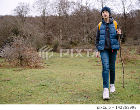 Hiking young person in nature with a stick Hiking young person in nature with a stick 142865998