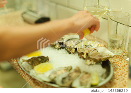 Hand squeezing lemon on fresh oysters 142866259