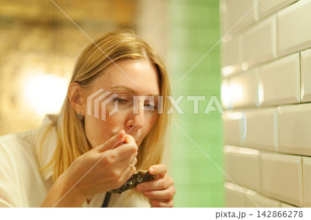 Woman eating oyster in restaurant Woman eating oyster in restaurant 142866278
