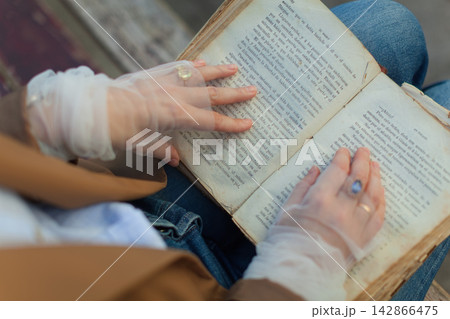 Hands reading vintage book with gloves 142866475