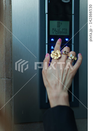 Hand pressing button on modern intercom 142866530