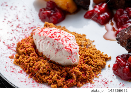 Cream quenelle on brown crumble with red berry powder close Cream quenelle on brown crumble with red berry powder close 142866651