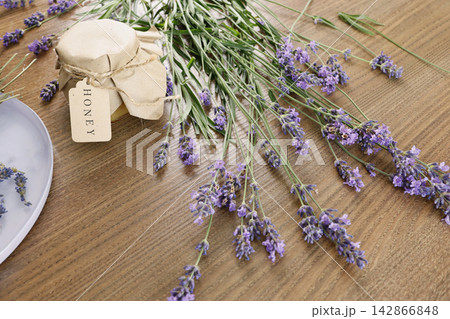Lavender honey jar paper lid text label honey wooden table background. Purple lavender flower bouquet bunch top view craft food product packaging. Organic sweet dessert artisan market flat lay concept 142866848