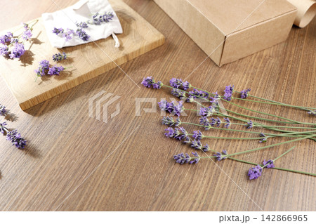Handmade lavender sachet pouch with blank kraft tag mockup on wood. Cozy home fragrance aromatherapy raw materials presentation. Minimalist rustic flat lay style design composition copy space banner f Handmade lavender sachet pouch with blank kraft tag mockup on wood. Cozy home fragrance aromatherapy raw materials presentation. Minimalist rustic flat lay style design composition copy space banner f 142866965