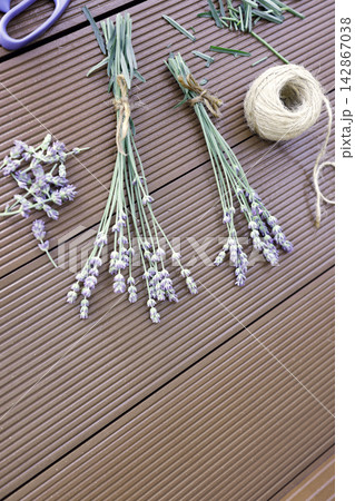 Lavender stems scissors twine ball on wooden background process of making bouquets. Dried organic lavender preparation workspace flat lay view composition. Handcraft hobby workspace with purple flower Lavender stems scissors twine ball on wooden background process of making bouquets. Dried organic lavender preparation workspace flat lay view composition. Handcraft hobby workspace with purple flower 142867038