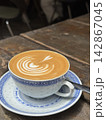 Fresh hot cafe latte with delicate heart latte art served in a traditional Chinese porcelain teacup and saucer on a rustic wooden table at a cafe in Hong Kong 142867045
