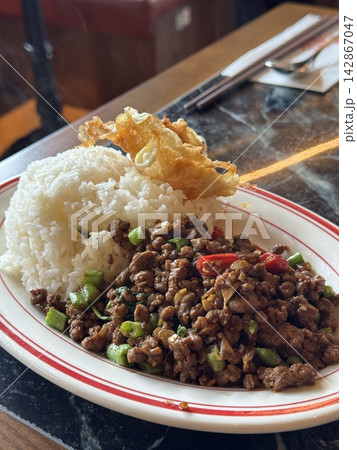 Authentic Thai stir-fried minced pork with holy basil and chili (Pad Kra Pao) served with steam rice and a crispy fried egg at a Thai restaurant in Hong Kong 142867047