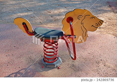 Empty lion spring rocker waits for young riders in sunlit playground. Empty lion spring rocker waits for young riders in sunlit playground. 142869736