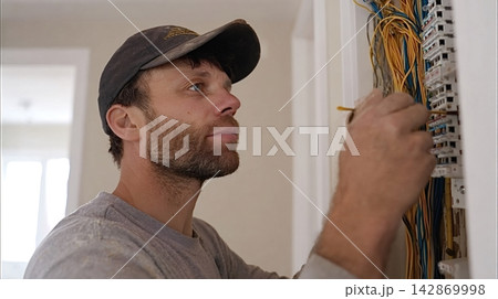 Electrician installing wiring in fuse box during electrical work 142869998