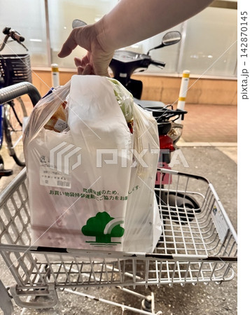 自転車の前かごに買い物袋を載せる日本の日常風景 142870145