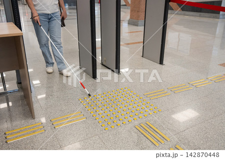 A blind woman walks through a metal detector. A blind woman walks through a metal detector. 142870448