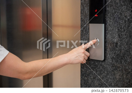 A woman calls an elevator. Tactile buttons for the visually impaired. 142870573