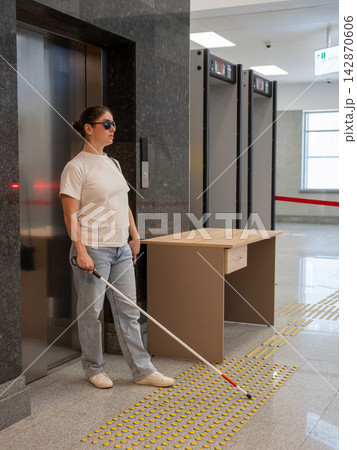 A blind woman exits an elevator. A blind woman exits an elevator. 142870606