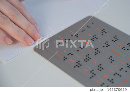 A woman learns to read Braille.  142870629