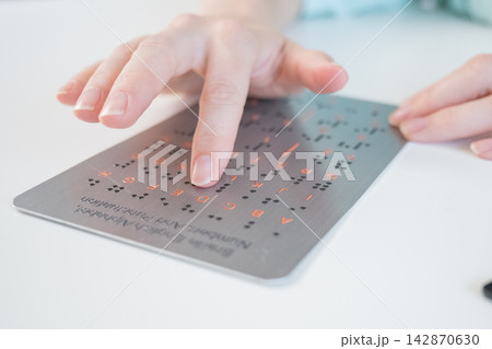 A blind woman learns the English alphabet from a braille sign. A blind woman learns the English alphabet from a braille sign. 142870630