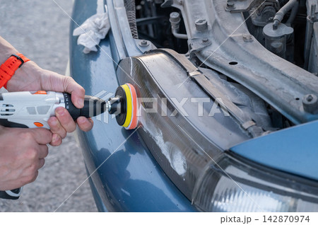 The process of polishing car headlights outdoors.  142870974