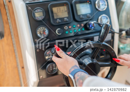 Women's hands at the helm of a yacht.  142870982