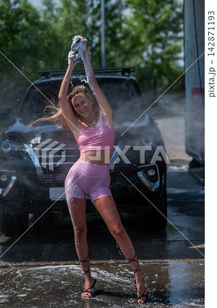 A Caucasian woman washes her car with a foam sponge. A Caucasian woman washes her car with a foam sponge. 142871193