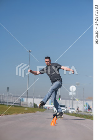 A Caucasian man rollerblades around the slalom course. A Caucasian man rollerblades around the slalom course. 142871583