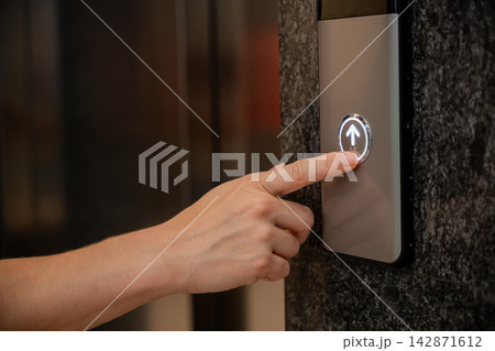 A woman calls an elevator. Tactile buttons for the visually impaired. A woman calls an elevator. Tactile buttons for the visually impaired. 142871612