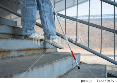 A blind woman descends a staircase. Close-up of her feet and a tactile stick. A blind woman descends a staircase. Close-up of her feet and a tactile stick. 142871615