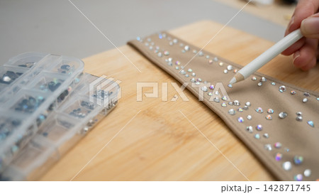 A woman decorates her gymnastics costume with rhinestones. Rhythmic gymnastics.  142871745