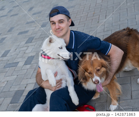 A man hugs his two dogs while on a walk. A man hugs his two dogs while on a walk. 142871863