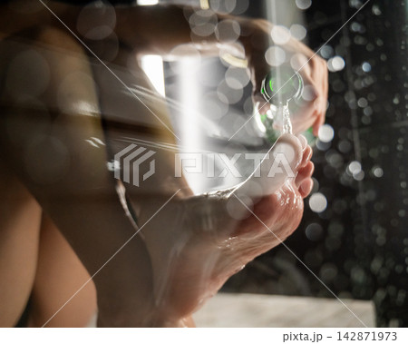 Foot fetish. A woman pours beer from a bottle onto her toes. Foot fetish. A woman pours beer from a bottle onto her toes. 142871973