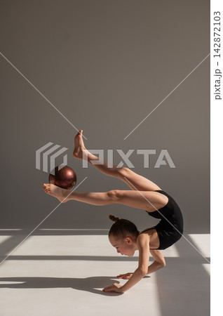 Little gymnast posing with a ball on a white background. Little gymnast posing with a ball on a white background. 142872103