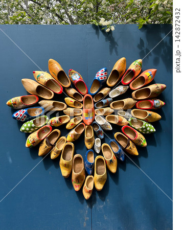 Colorful wooden clogs arranged in a heart shape on a blue wall Colorful wooden clogs arranged in a heart shape on a blue wall 142872432