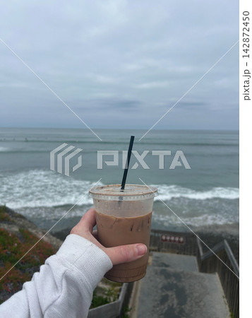 Holding an iced coffee with a view of the ocean Holding an iced coffee with a view of the ocean 142872450